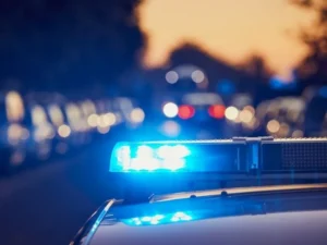 Radiowóz policyjny z włączonym niebieskim sygnałem świetlnym na drodze nocą