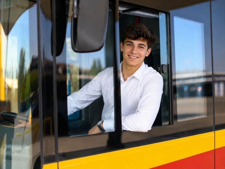 Młody kierowca autobusu siedzący za kierownicą po uzyskaniu prawa jazdy kategorii D od 18. roku życia
